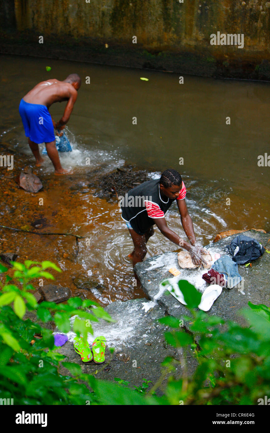 Les jeunes hommes s'en laver les jeans dans un ruisseau, Bamenda, Cameroun, Afrique Banque D'Images