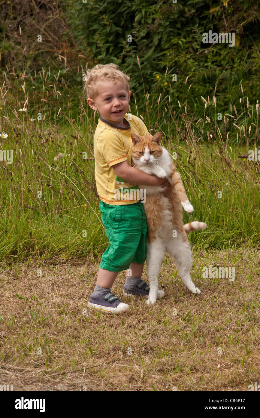 Deux heureux mignon petit garçon tenant un chat de gingembre à l'extérieur, Hampshire, Angleterre, Royaume-Uni. Banque D'Images