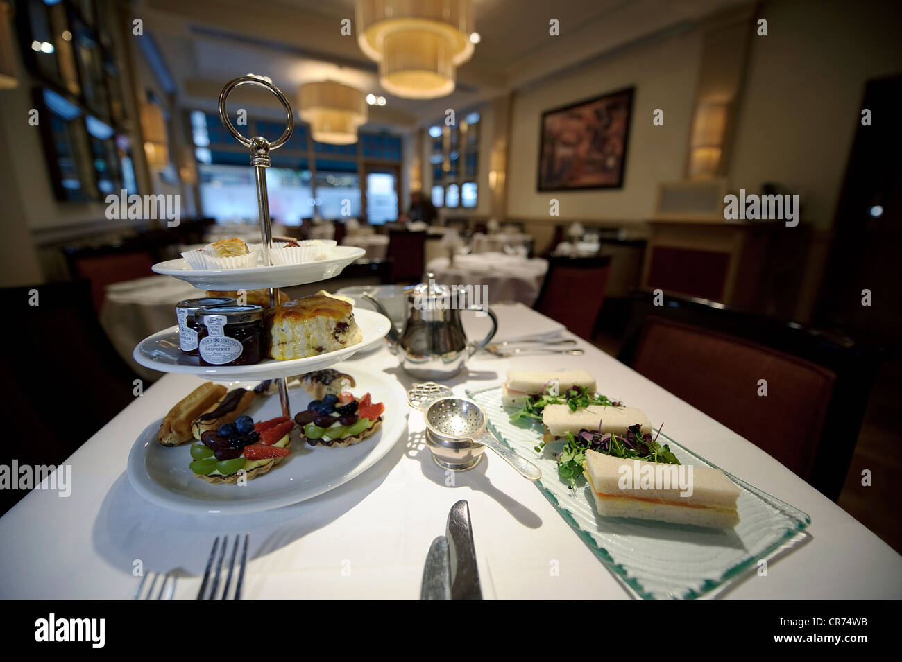 Table de restaurant avec posh thé anglais l'après-midi avec sandwichs gâteaux scones couverts Banque D'Images