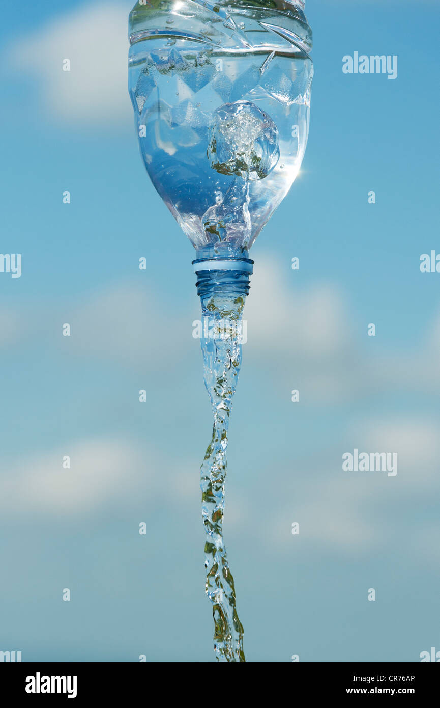 Verser de l'eau potable à partir d'une bouteille en plastique contre un ciel bleu Banque D'Images
