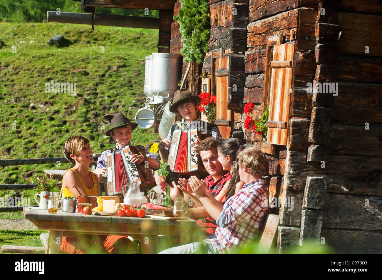 L'Autriche, Salzburg County, les hommes et les femmes siégeant au chalet de montagne, à l'écoute de musiciens Banque D'Images