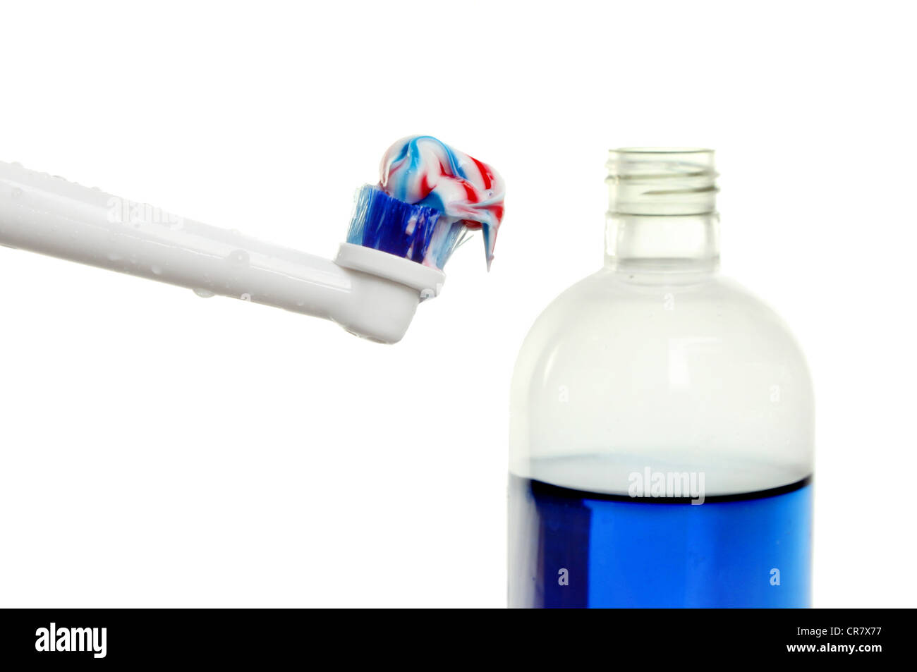 Gros plan du dentifrice sur une brosse à dents avec une bouteille de rince-bouche dans l'arrière-plan Banque D'Images