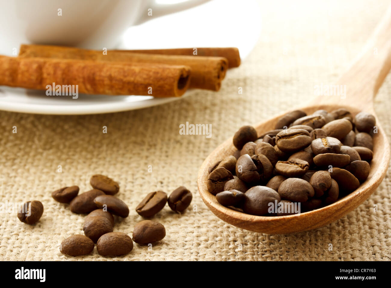 Grains de café dans une cuillère en bois avec des bâtons de cannelle et tasse à café Banque D'Images