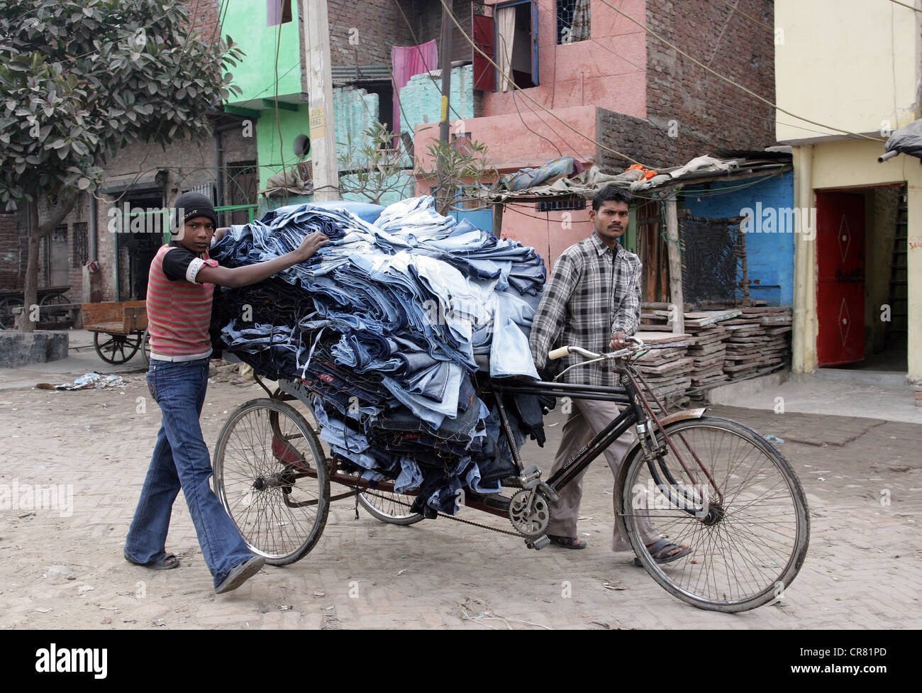 Pousse-pousse comme un transporteur d'un jeans couture dans le bidonville colonie Janata à New Delhi, Inde Banque D'Images