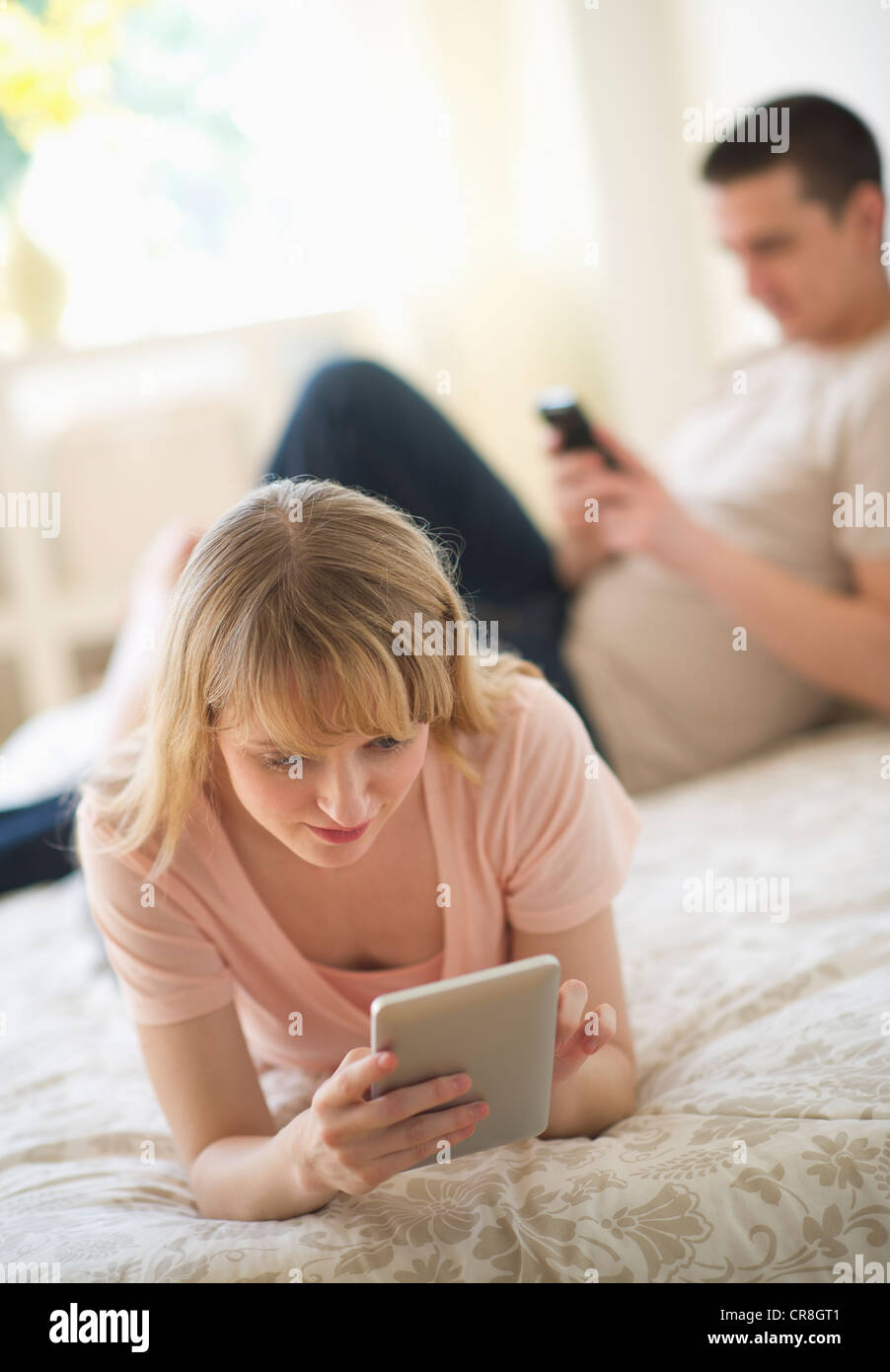 USA, New Jersey, Jersey City, Couple lying on bed et l'aide de dispositifs numériques Banque D'Images