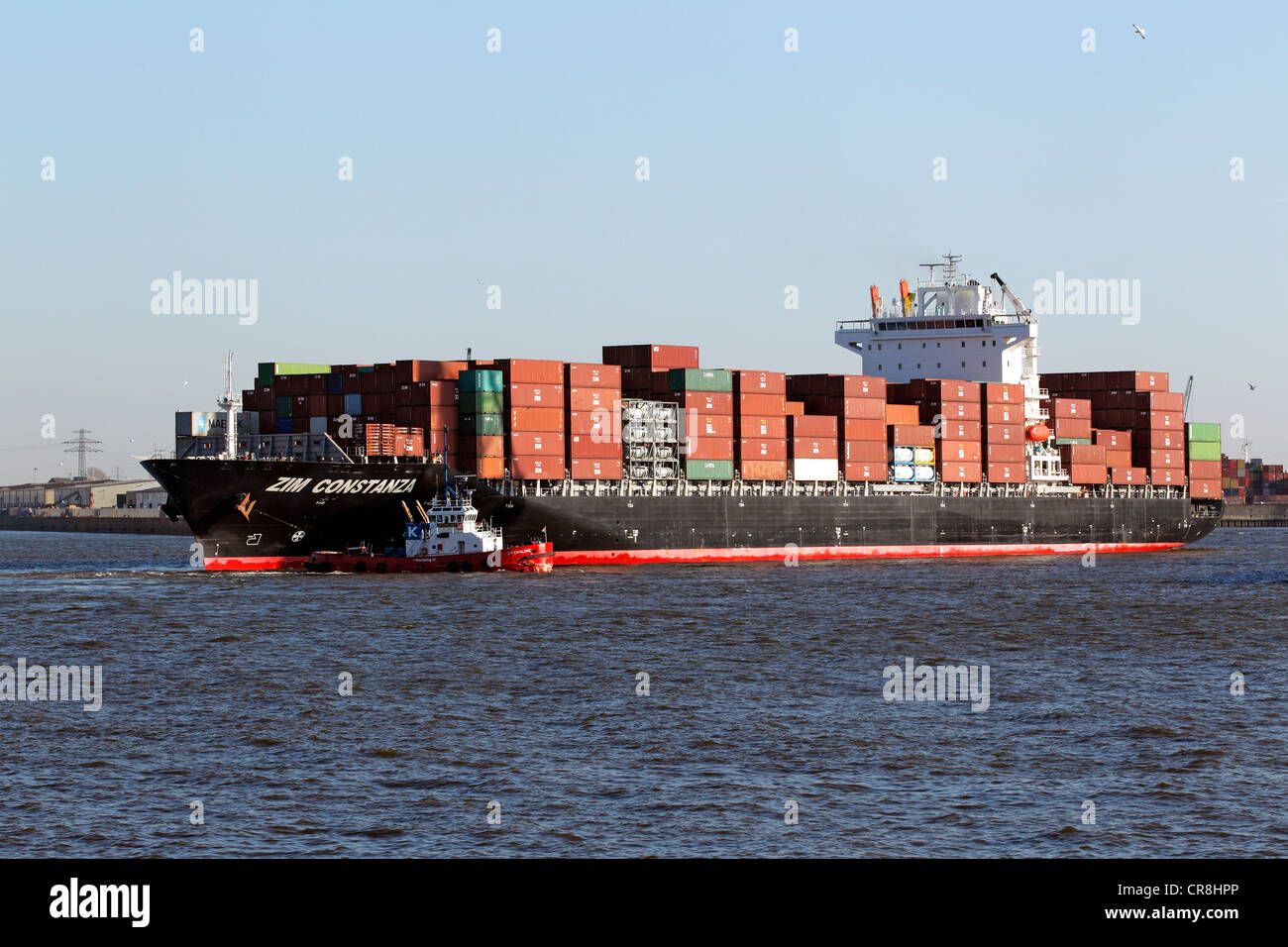 Tug boat et porte-conteneurs ZIM Constanza sur l'Elbe dans le port de Hambourg, Allemagne Banque D'Images