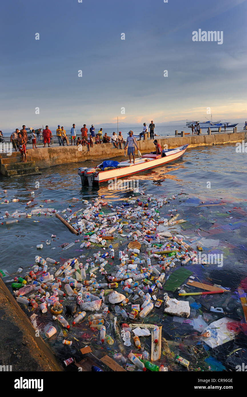 Les pêcheurs débarquent leurs prises et de l'amener jusqu'au murs de quai, débris flottants en plastique à l'avant, l'île de Biak Biak, Kota Banque D'Images