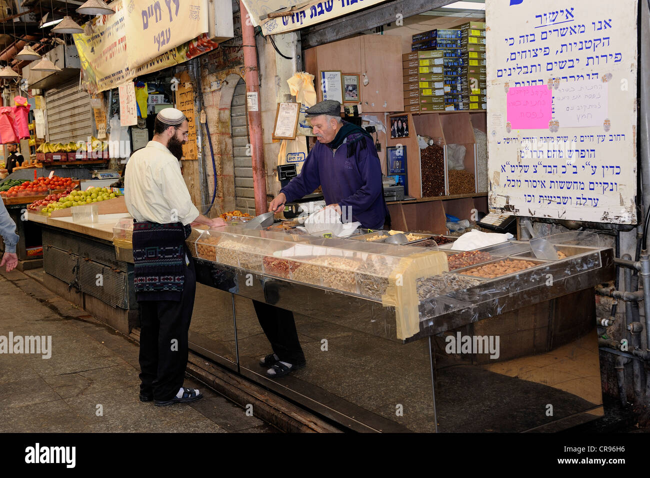 L'homme juif portant une kippa achat d'écrous sur le marché Mahane Yehuda à partir d'un marchand juif, Jaffa Road, Jérusalem, Israël Banque D'Images