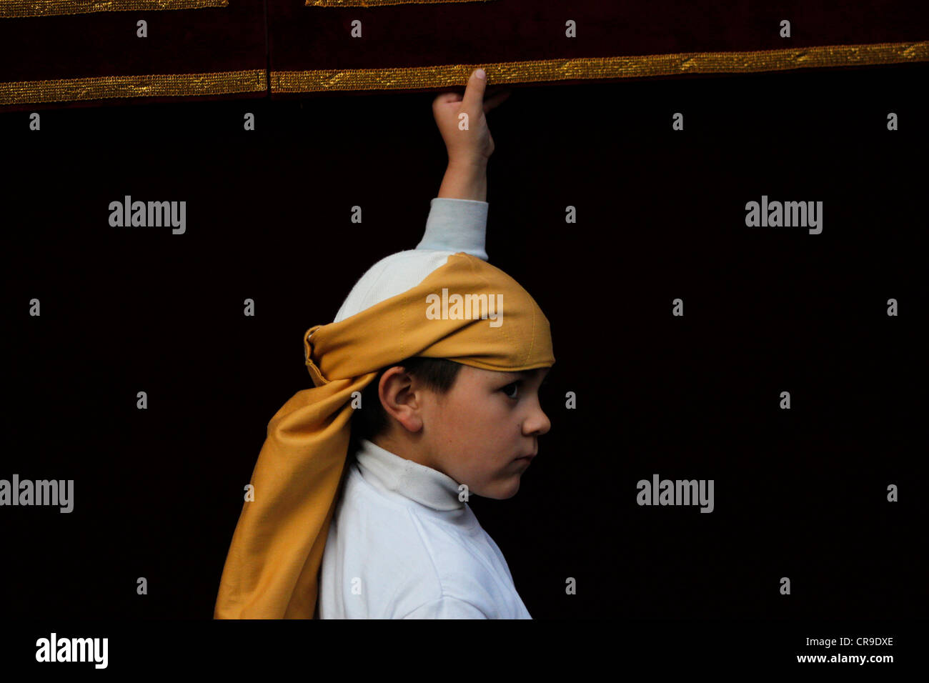 Un garçon marche par un discours du trône au cours d'une procession de la Semaine Sainte de Pâques dans la région de Puente Genil, dans la province de Cordoba, Espagne Banque D'Images