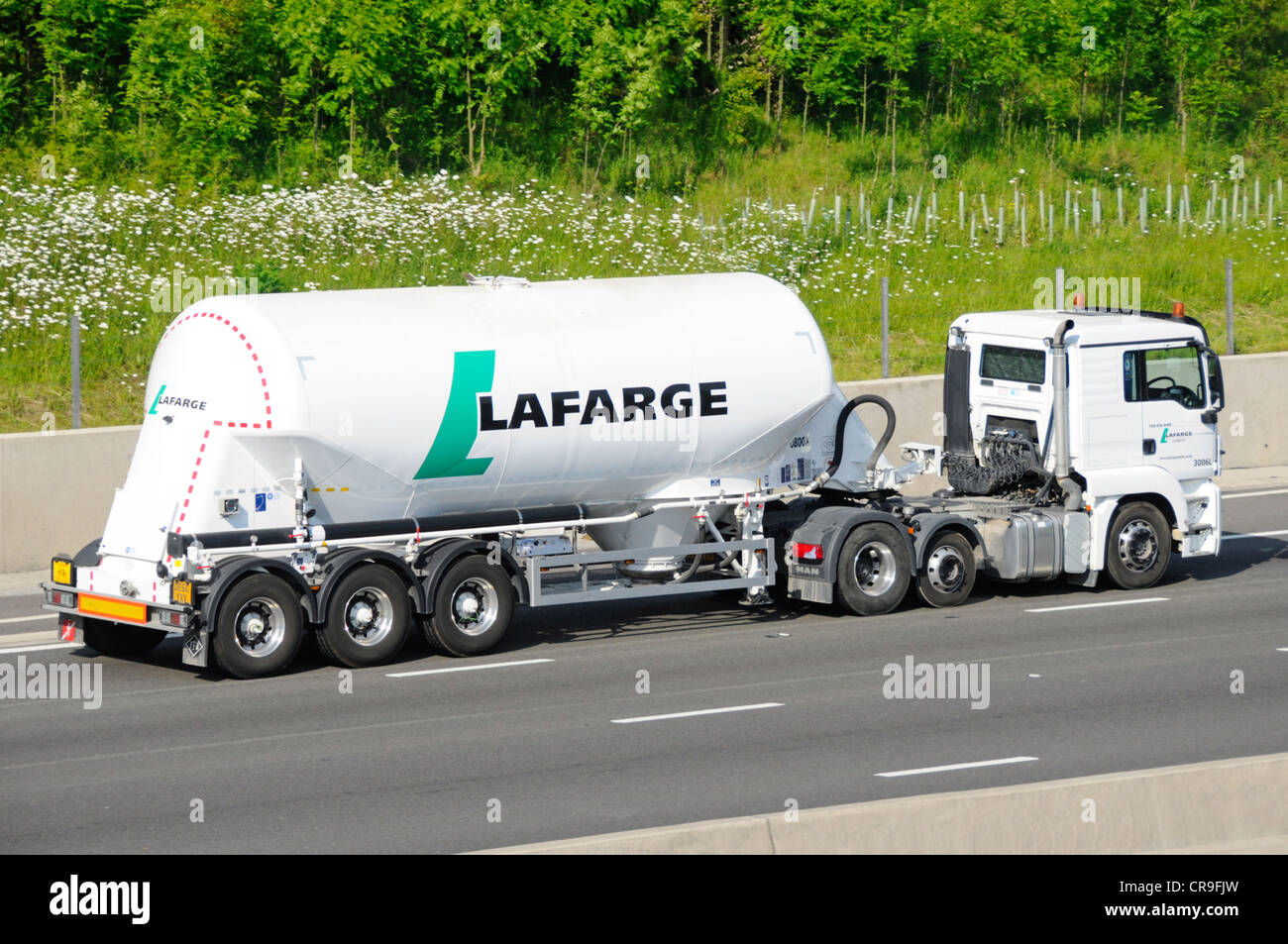 Vue latérale porte-poudre de ciment en vrac LaFarge dans une remorque de camion-citerne articulée tractée par camion hgv blanc roulant le long de l'autoroute M25 Essex Angleterre Royaume-Uni Banque D'Images