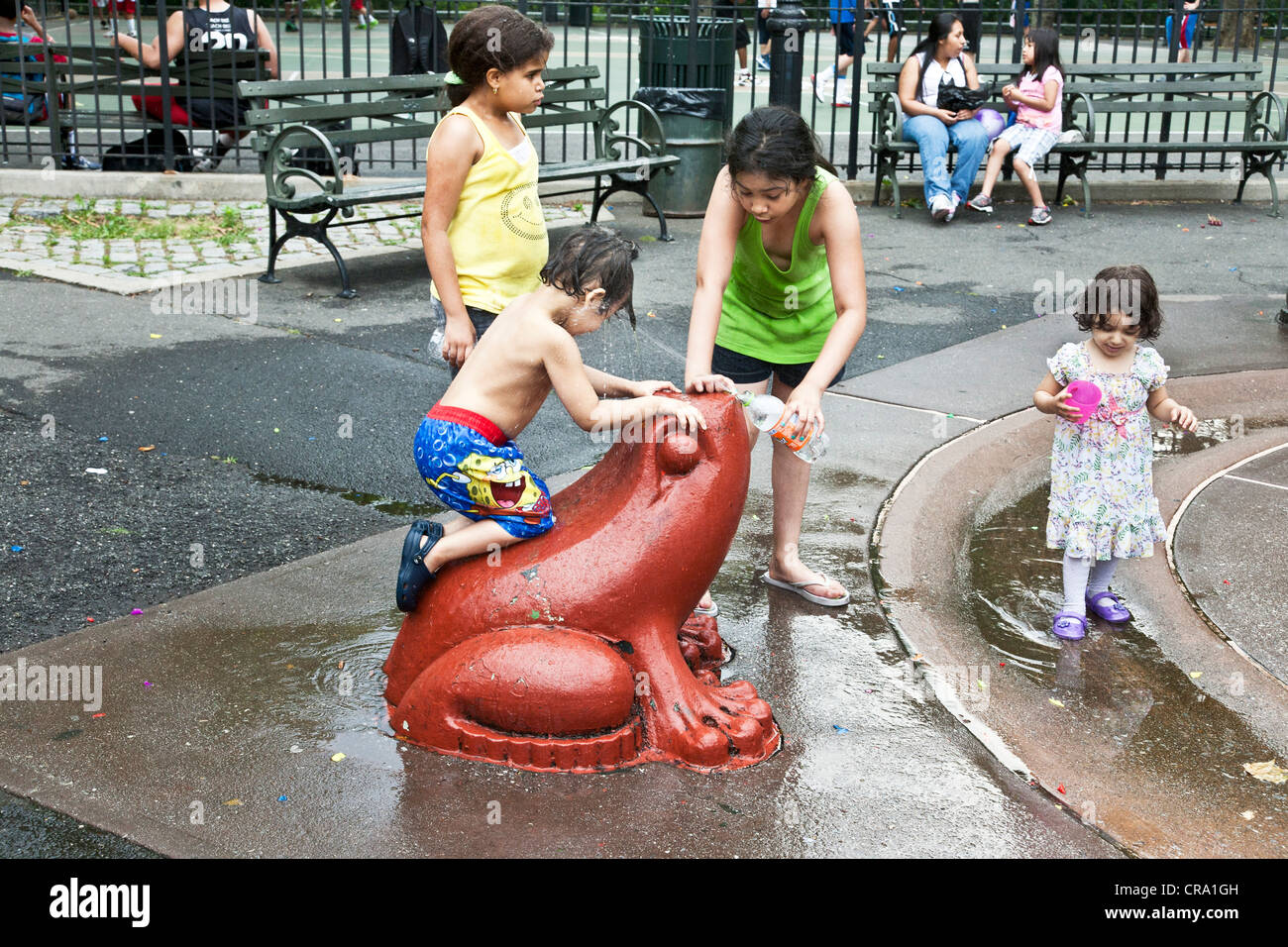 Happy group of multiethnic enfants jouer sur grenouille colorée en fonction de l'eau de DeWitt Clinton Park dans le quartier Hell's Kitchen Banque D'Images
