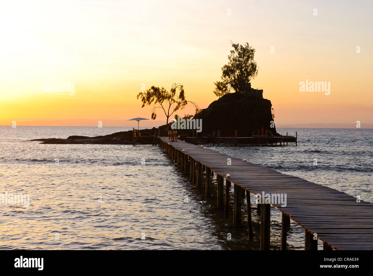 Jetty menant à une petite île rocheuse avec des chaises longues au coucher du soleil, l'île de Santa Maria, Madagascar, Afrique Banque D'Images