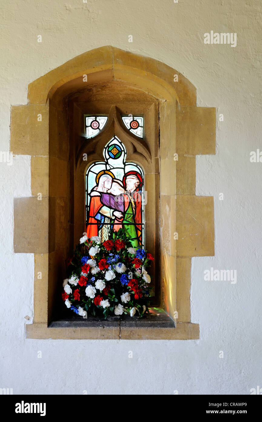 Au plomb vitraux fenêtre dans un mur en pierre sculptée avec niche, blanc, de mur et rouge, blanc et bleu de fleurs. Banque D'Images