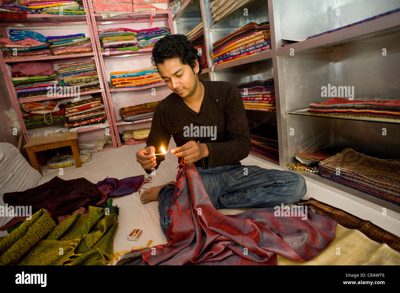Vendeur prouvant l'authenticité la soie avec un test de la flamme, de la vieille ville de Varanasi, Uttar Pradesh, Inde, Asie Banque D'Images