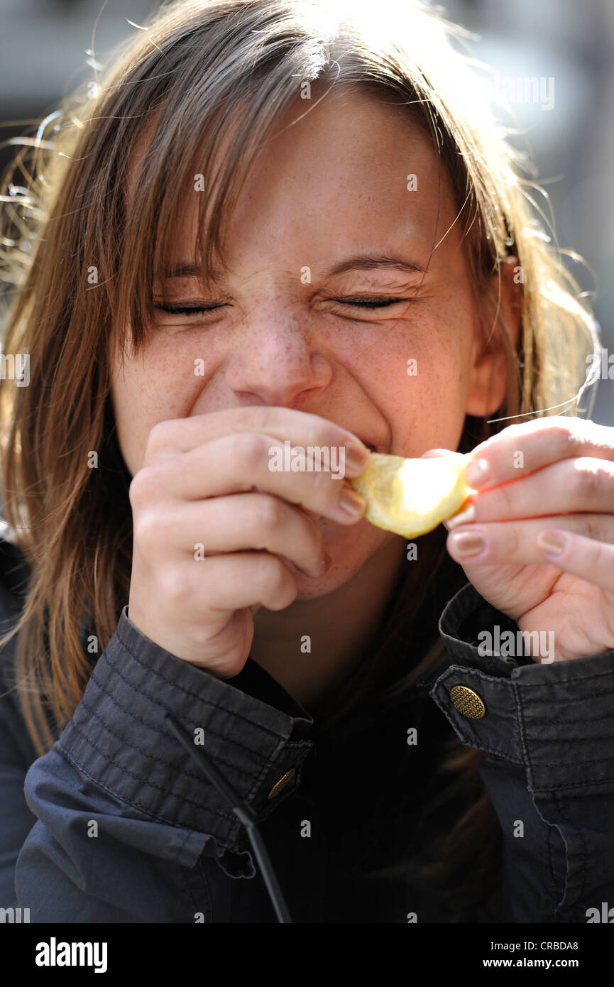 Jeune femme mordre dans le citron et rire, Paris, France, Europe Banque D'Images