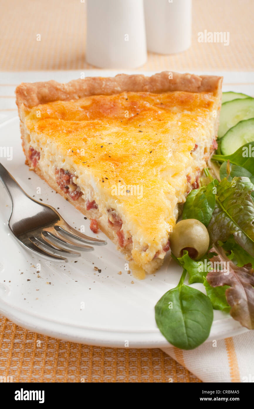 Une tranche de la quiche lorraine ou du bacon et des oeufs, flan sur une assiette avec la salade. Banque D'Images