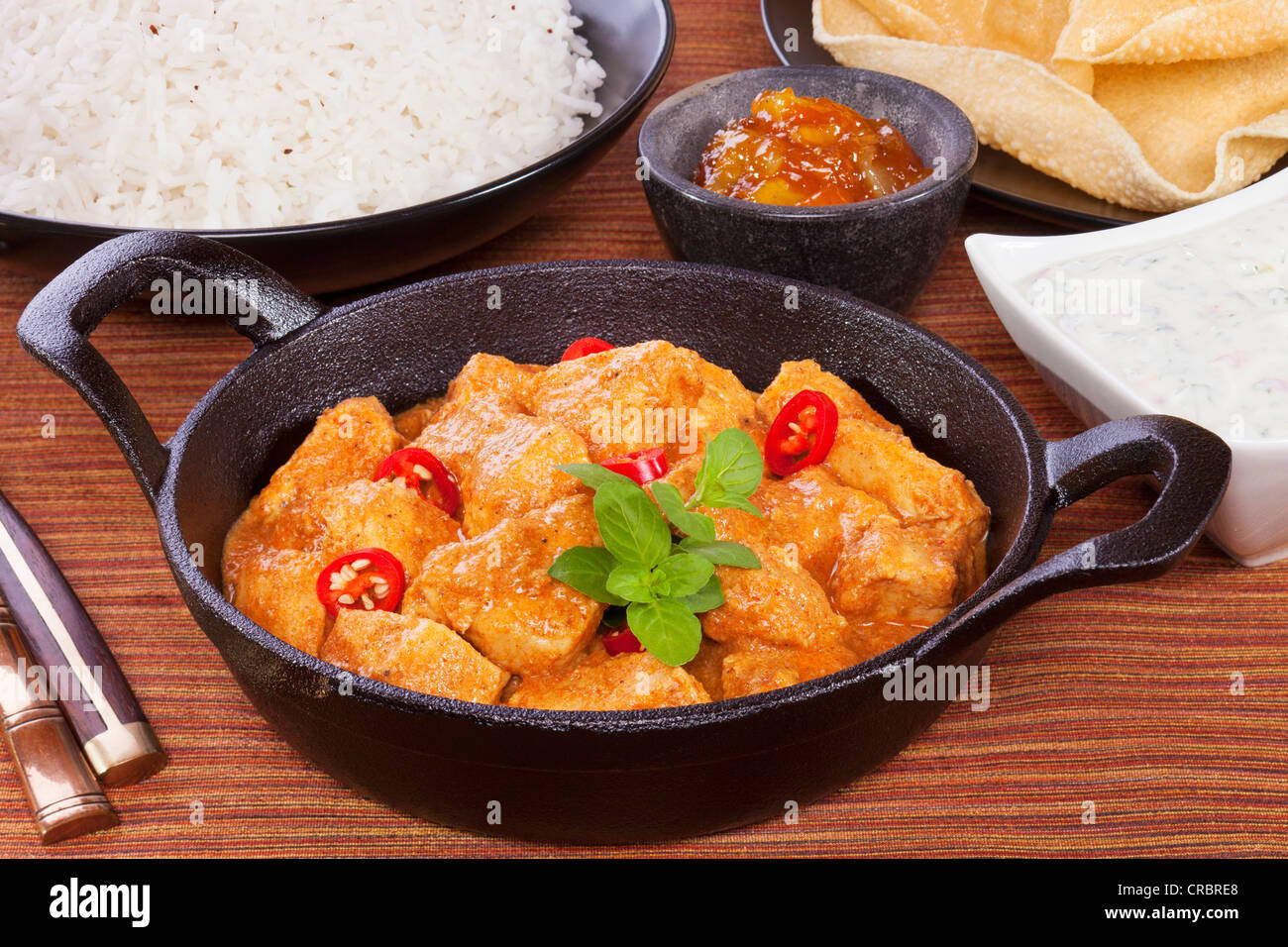 Curry Indien de poulet au beurre avec du riz, poppadums, Chutney de mangues et de concombre raita. Banque D'Images