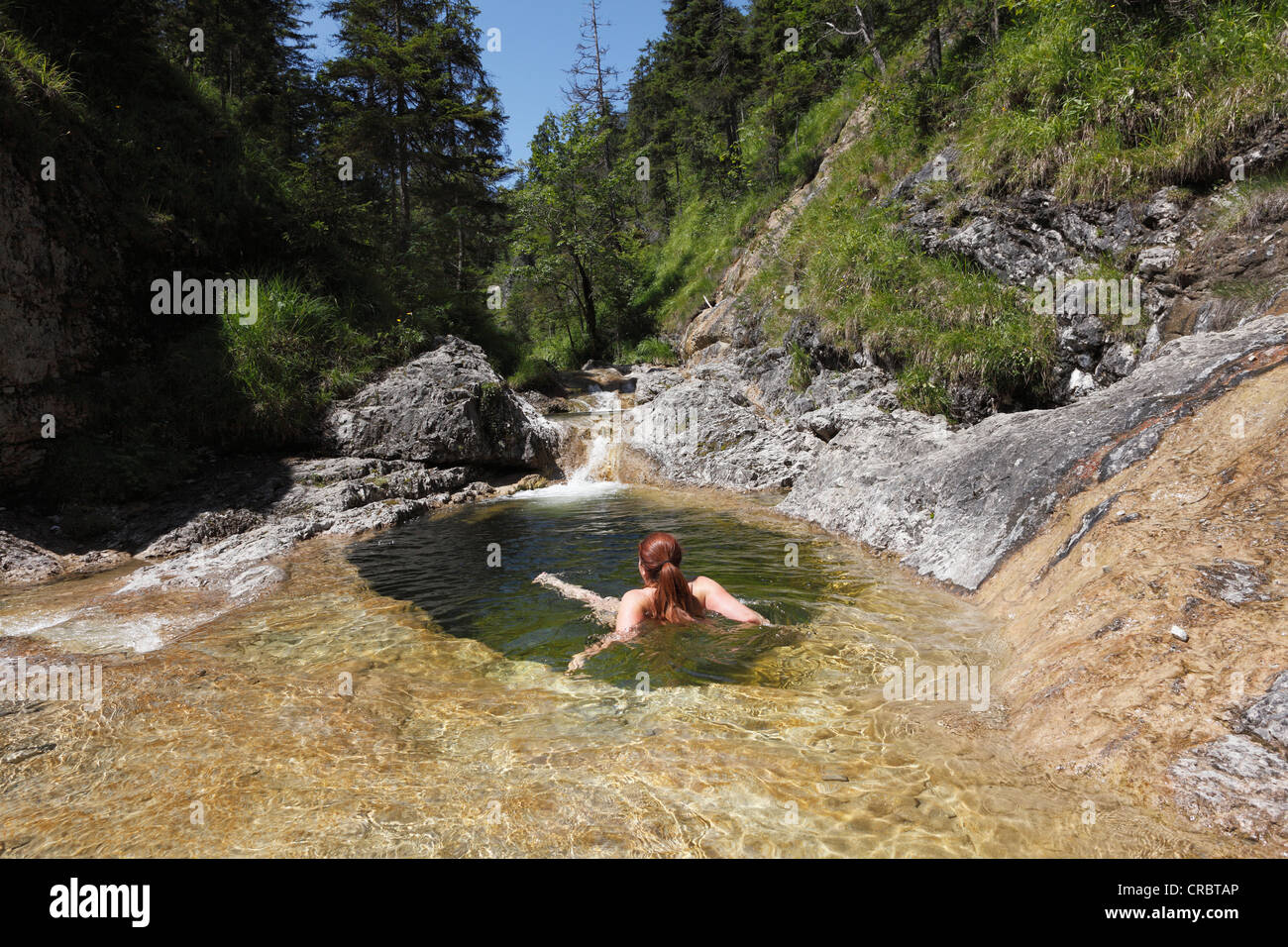 Femme baignant dans une piscine dans les rochers à Schronbach Schronbachtal stream, vallée, municipalité de Jachenau, Isarwinkel, Haute-Bavière Banque D'Images