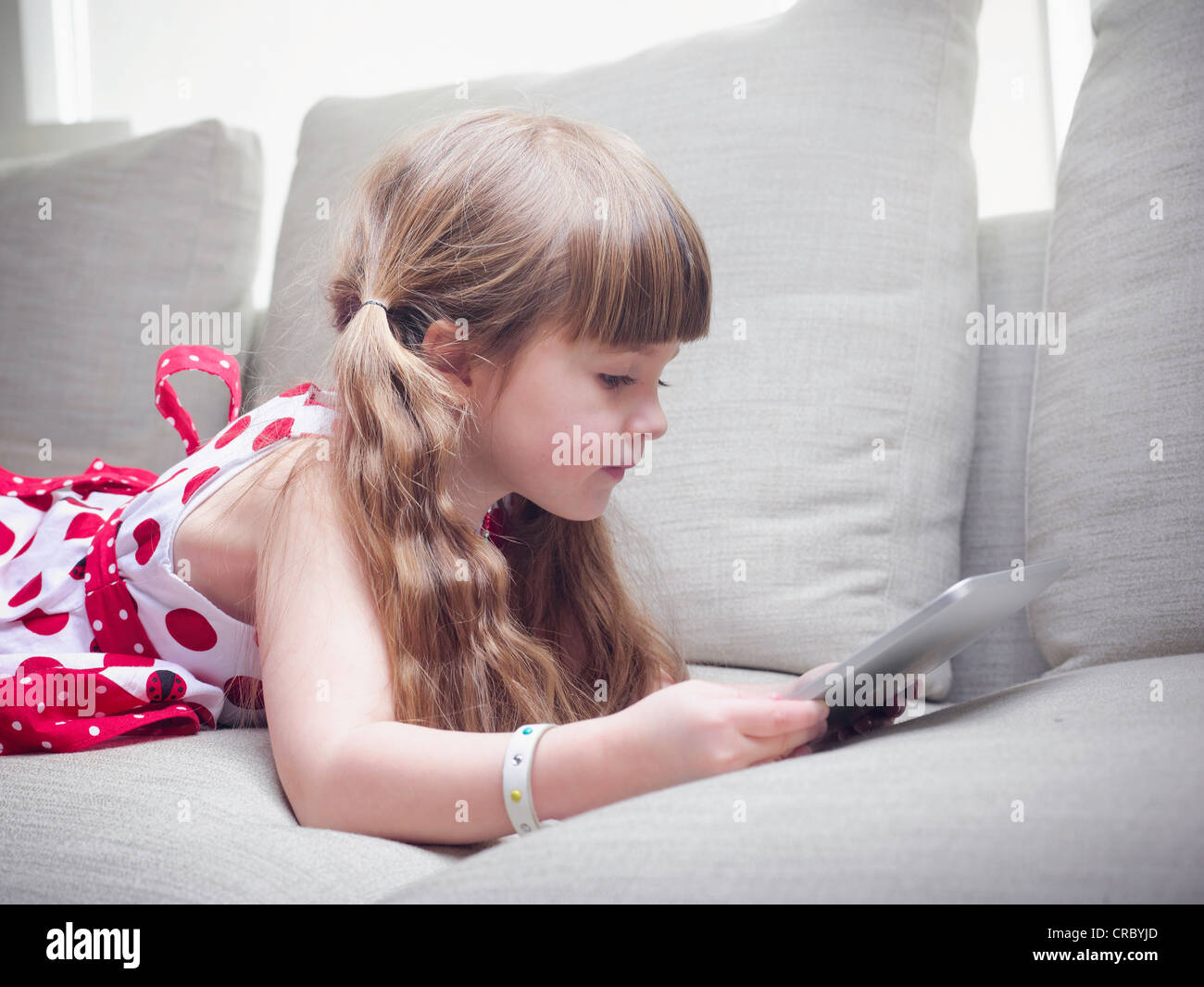 Girl using tablet computer on sofa Banque D'Images