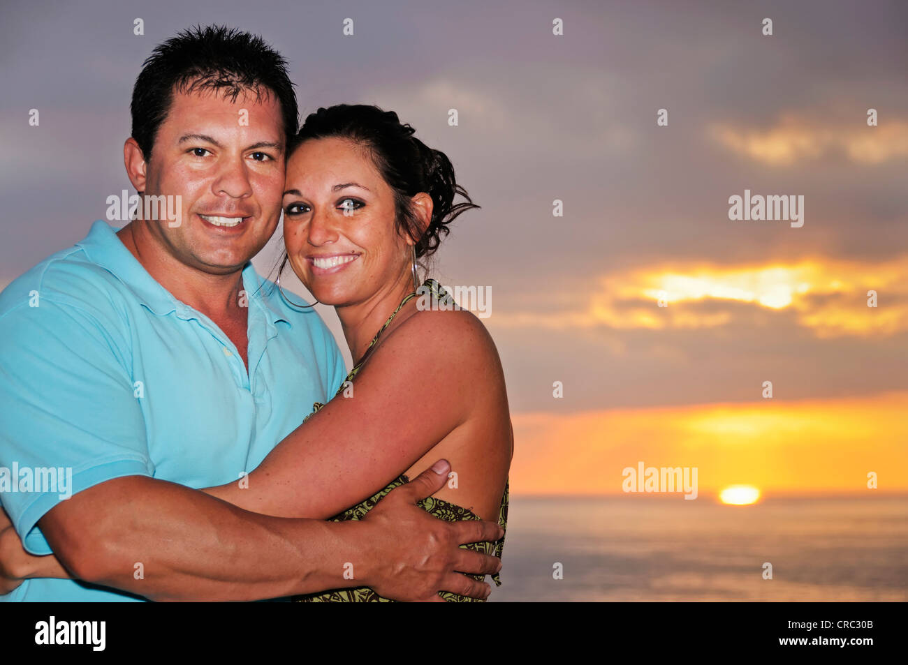 Smiling young adult couple hétérosexuel embrasse devant un coucher de soleil sur le pacifique à Puerto Vallarta, au Mexique. Banque D'Images