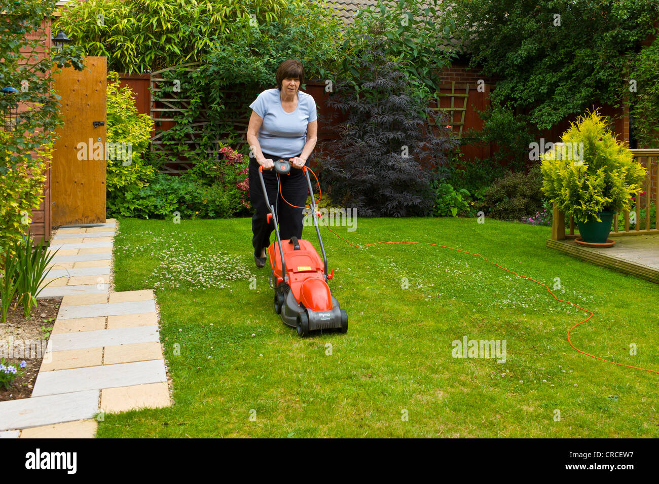 Femme mature de tondre la pelouse avec une tondeuse électrique Photo