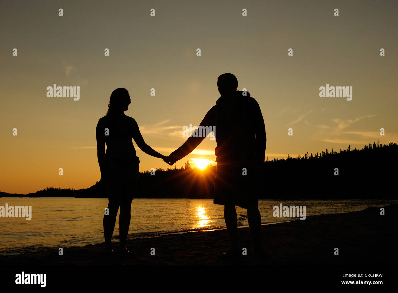 Couple holding hands sur les rives du lac Supérieur au coucher du soleil, de l'Ontario, Canada Banque D'Images