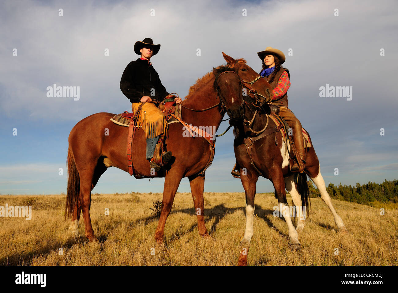 Une cowgirl et un cowboy assis sur leurs chevaux, Saskatchewan, Canada Banque D'Images