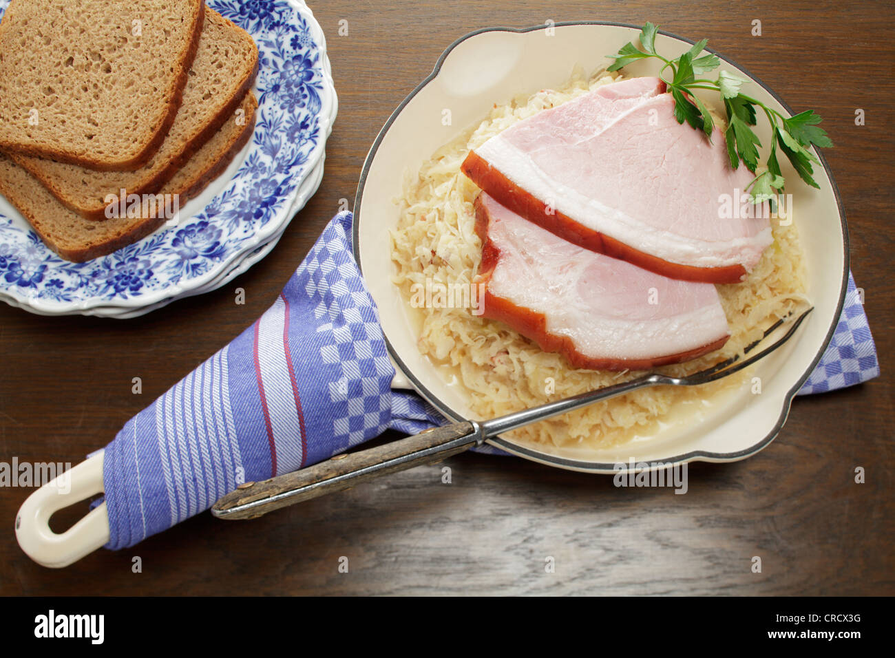 Rôti de porc avec grésillement servi dans une poêle sur la choucroute, les tranches de pain de seigle Banque D'Images