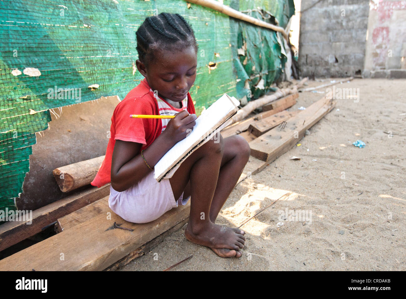 Une fille fait ses devoirs dans le bidonville de West Point de Monrovia, le comté de Montserrado, au Liberia, le lundi 2 avril 2012. Banque D'Images