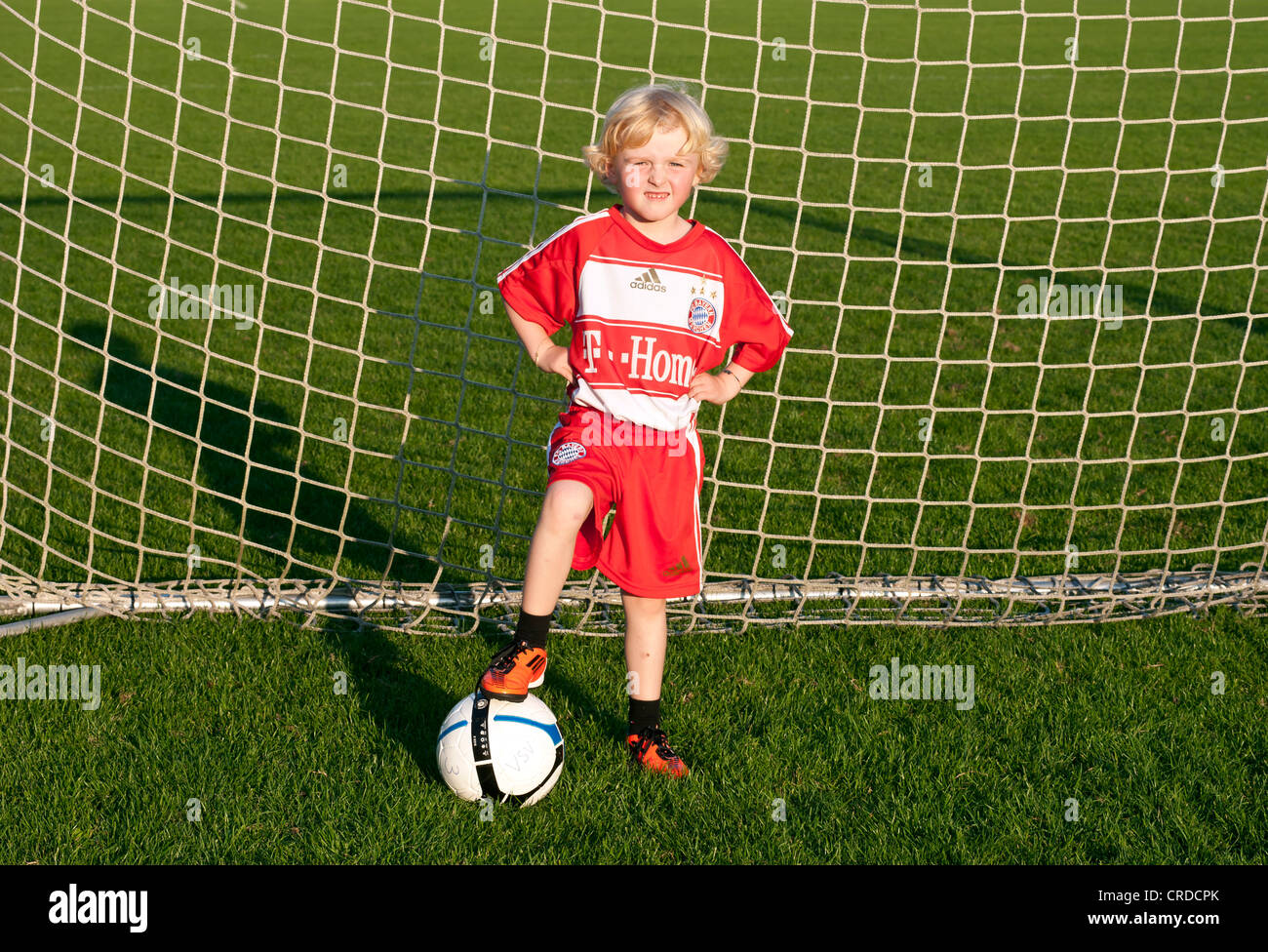 Petit garçon de cinq ans portant une robe de football FC Bayern Munich,  debout dans un but de football avec un ballon de foot Photo Stock - Alamy