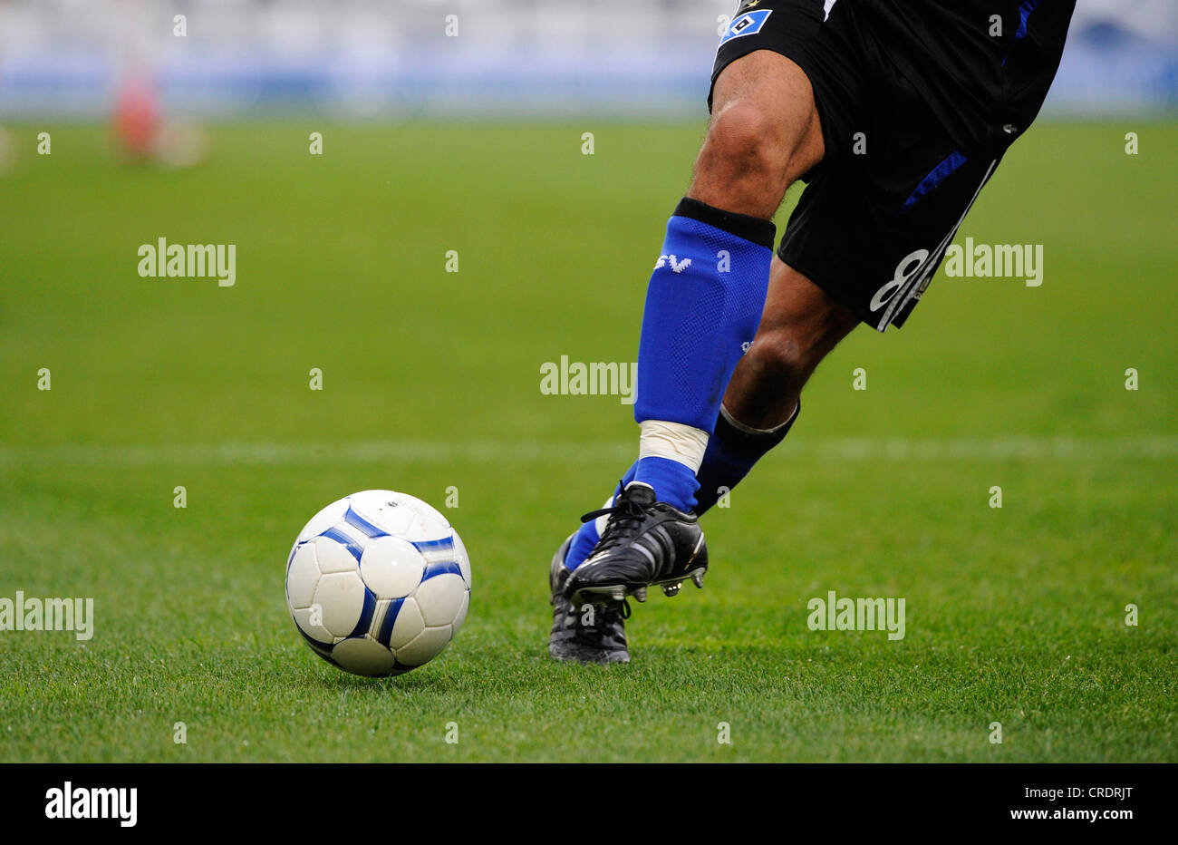 Les jambes d'un joueur de football et le football Banque D'Images