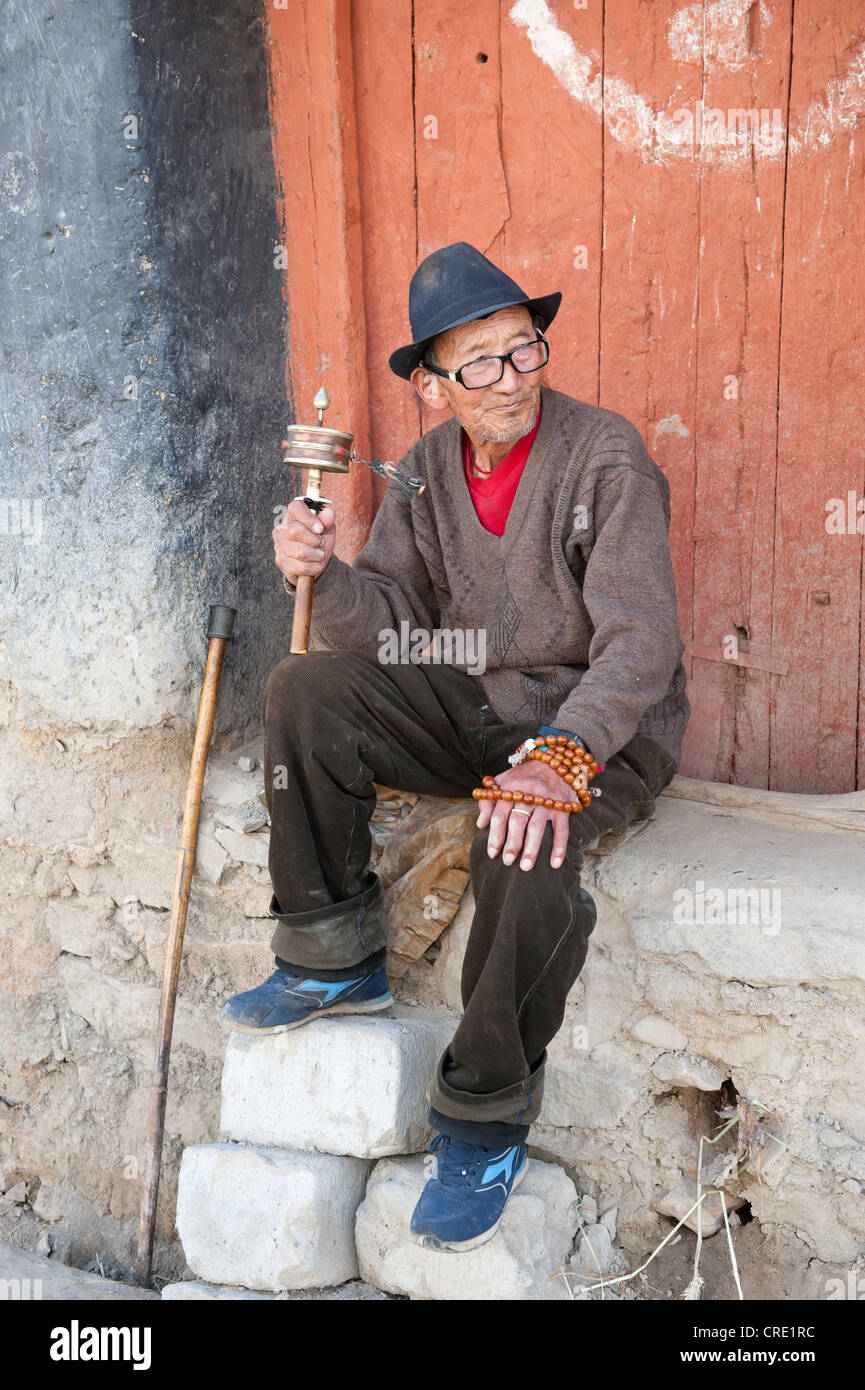 Tibetan assis en face d'une porte de tourner un moulin à prières, Luzhou, de l'Himalaya, le Tibet central, Ue-Tsang Banque D'Images