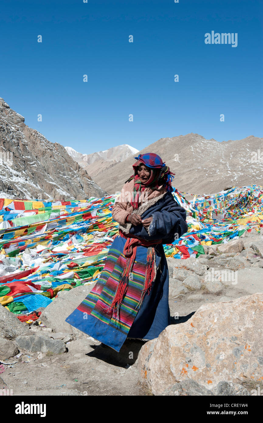 Le bouddhisme tibétain, de nombreux drapeaux de prière tibétains colorés, femme en costume traditionnel à la Dolma La Pass, 5670m, route de pèlerinage Banque D'Images