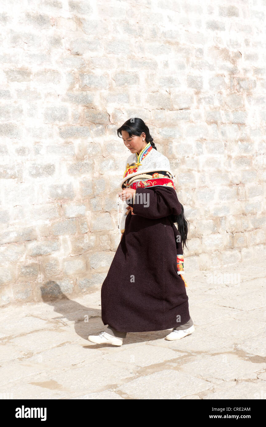 Le bouddhisme tibétain, jeune femme tibétaine religieuse marcher le long d'un mur, monastère de Ganden, l'Himalaya, le Tibet central, Ue-Tsang Banque D'Images