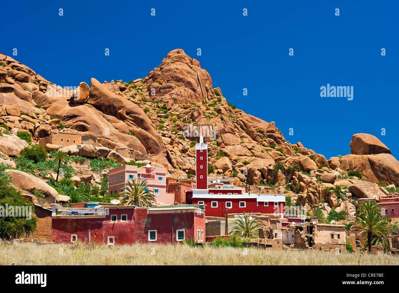 Petit village avec une mosquée et un minaret en face d'un paysage rocheux avec les rochers de granit, Tafraoute Banque D'Images