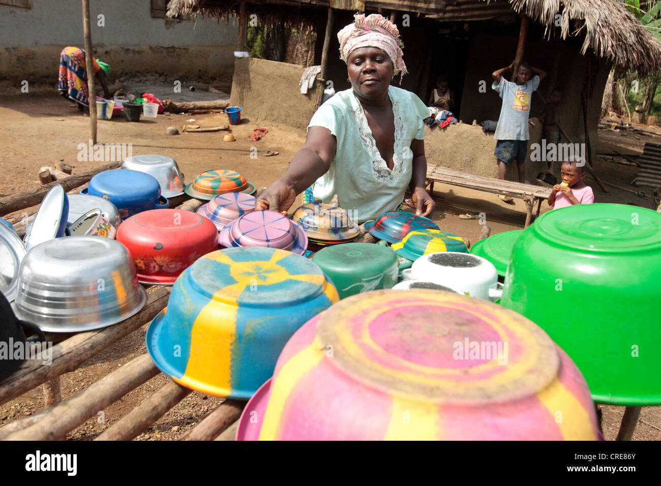 Une femme présente des bols, des pots et des plats internationaux sur un égouttoir, utilisé pour sécher la vaisselle au lieu de les poser directement sur le sol Banque D'Images