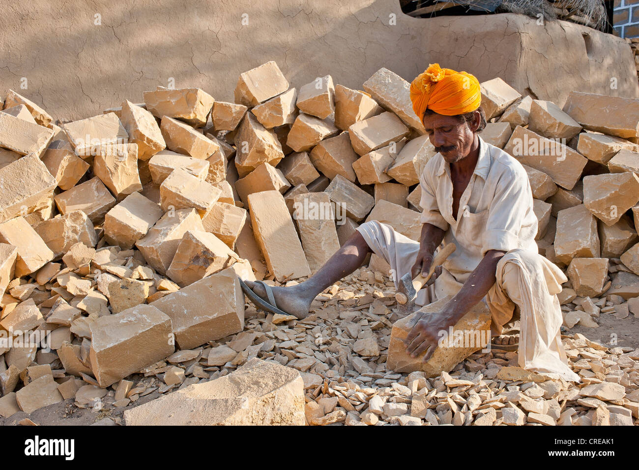 L'homme indien vêtu d'un dhoti traditionnel et turban, casser des pierres avec un marteau jusqu'à la taille appropriée pour le bâtiment Banque D'Images