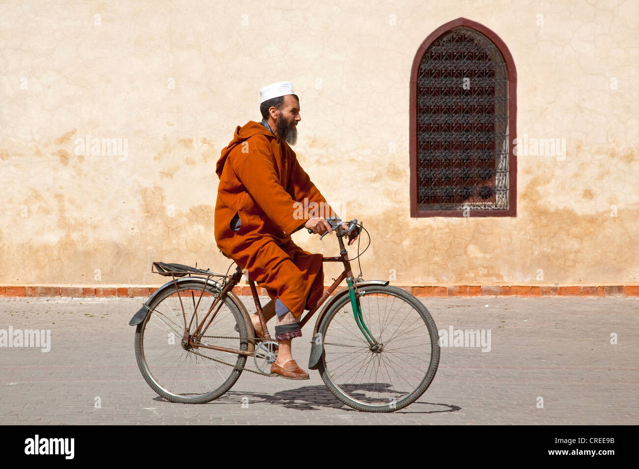 Cycliste Portant Une Djellaba Une Robe Traditionnelle Le Velo En Face De La Medersa Ben Youssef Dans La Medina Le Quartier Historique Photo Stock Alamy