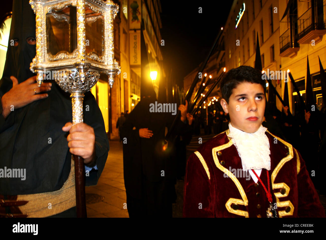 Procession d'une fraternité, Cofradia, pendant la Semaine Sainte, dans la nuit avec capots noir et le garçon en costume médiéval et à la recherche avec l'incrédulité, l'Espagne, Andalousie, Séville Banque D'Images