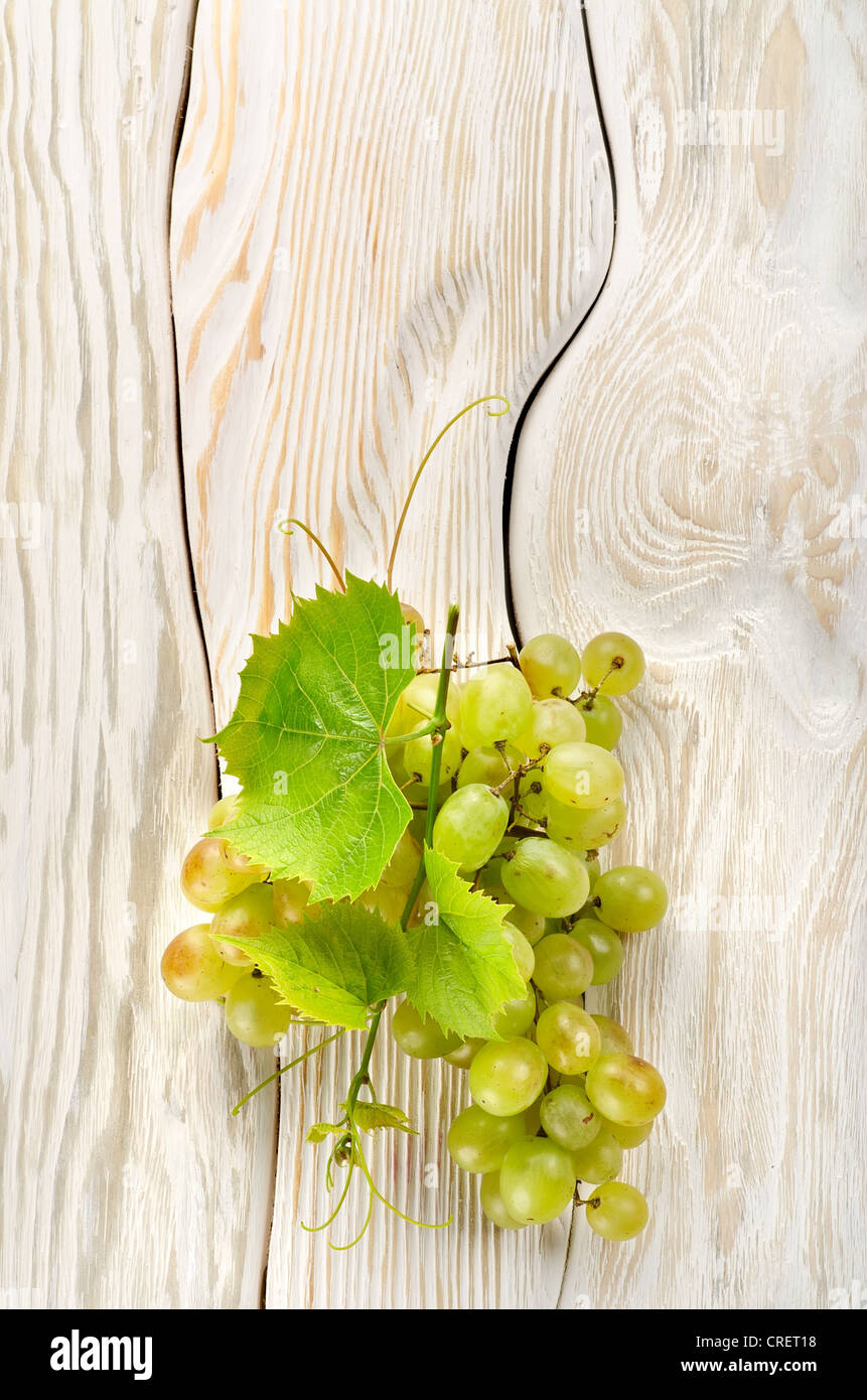 Raisins verts sur un fond de bois blanc Banque D'Images