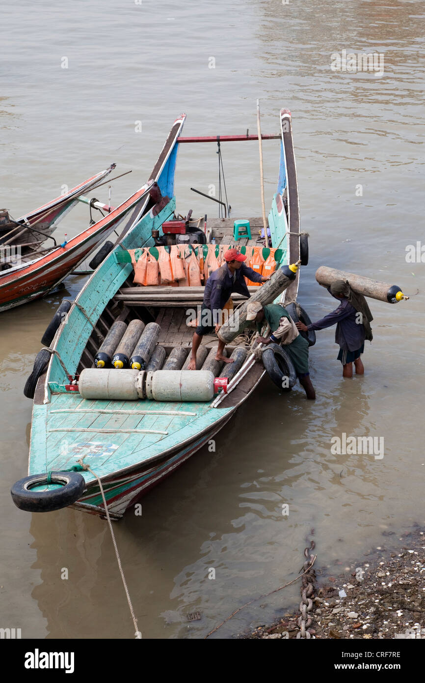Le Myanmar, Birmanie, Yangon. Chargement manuel des bouteilles d'oxygène en petit bateau, fleuve Yangon. Banque D'Images