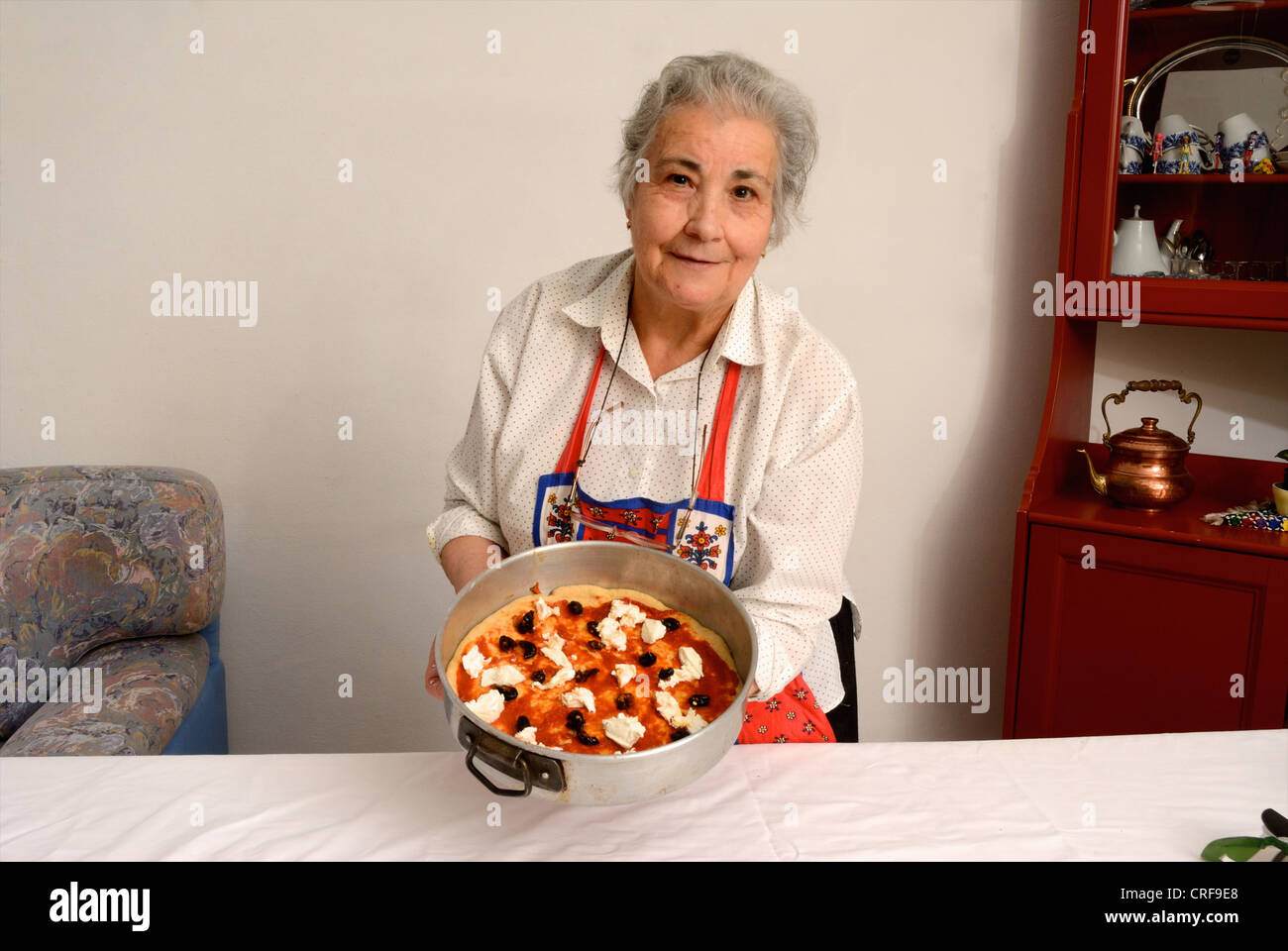 Femme plus âgée pizza dans la salle de séjour Banque D'Images