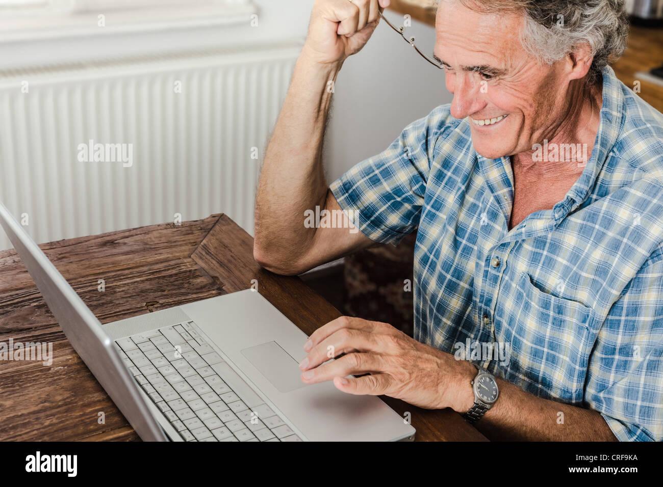 Older Man using laptop in kitchen Banque D'Images