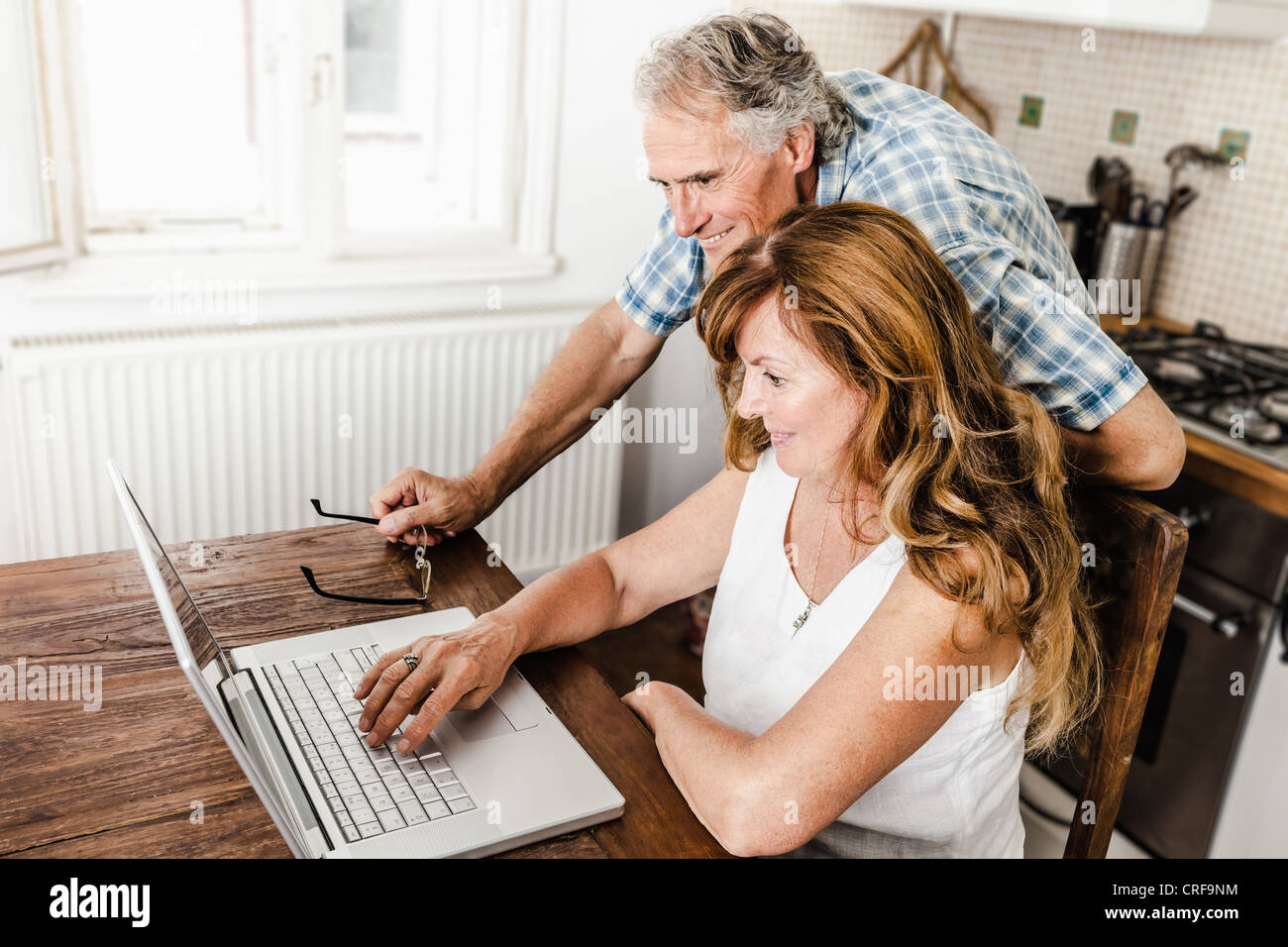 Vieux couple using laptop in kitchen Banque D'Images