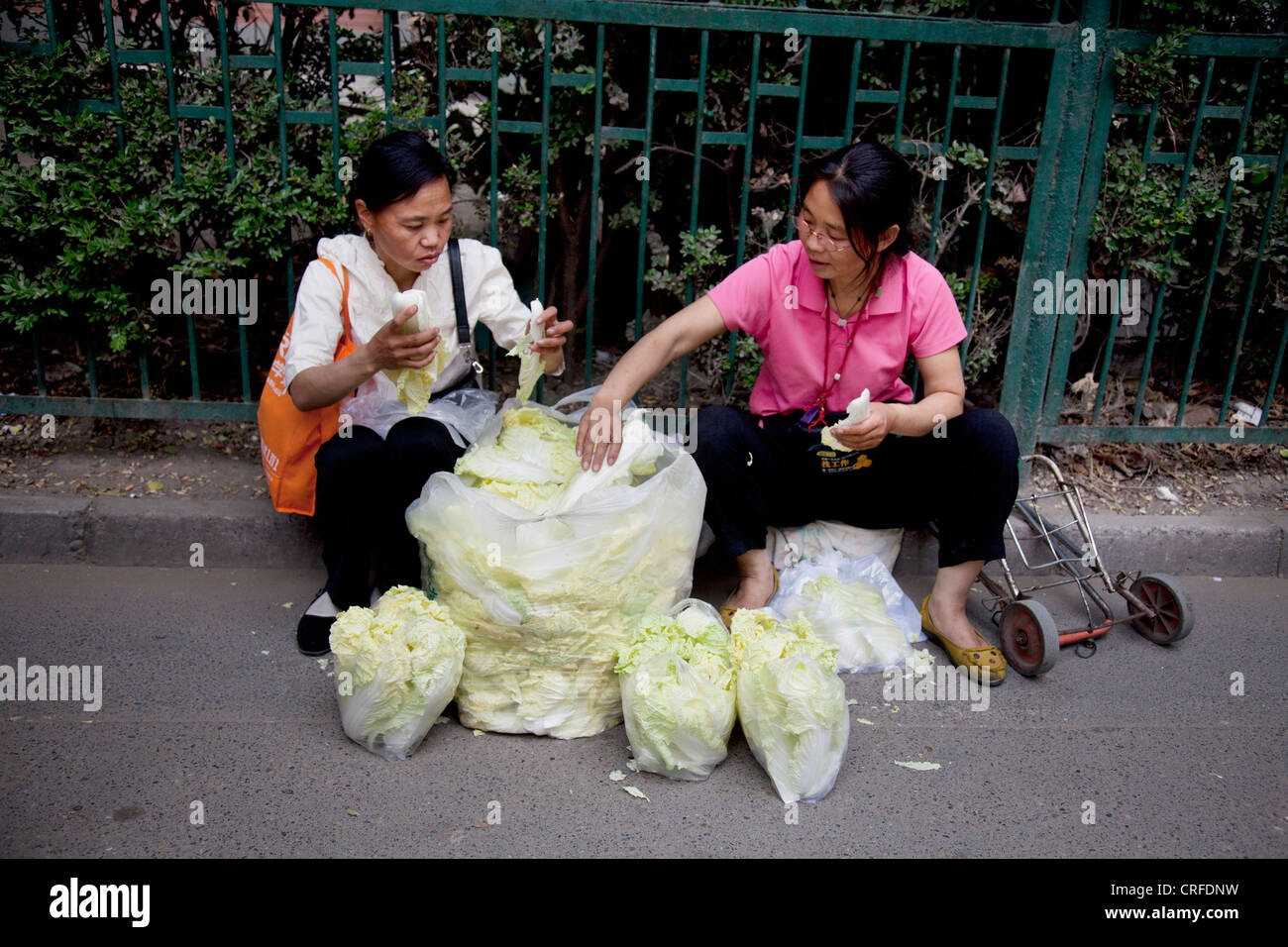 Les femmes vendent des feuilles de choux chinois dans un marché de rue dans une ancienne zone de style Chinois Fuchengmen, Dongcheng District de Beijing. Banque D'Images