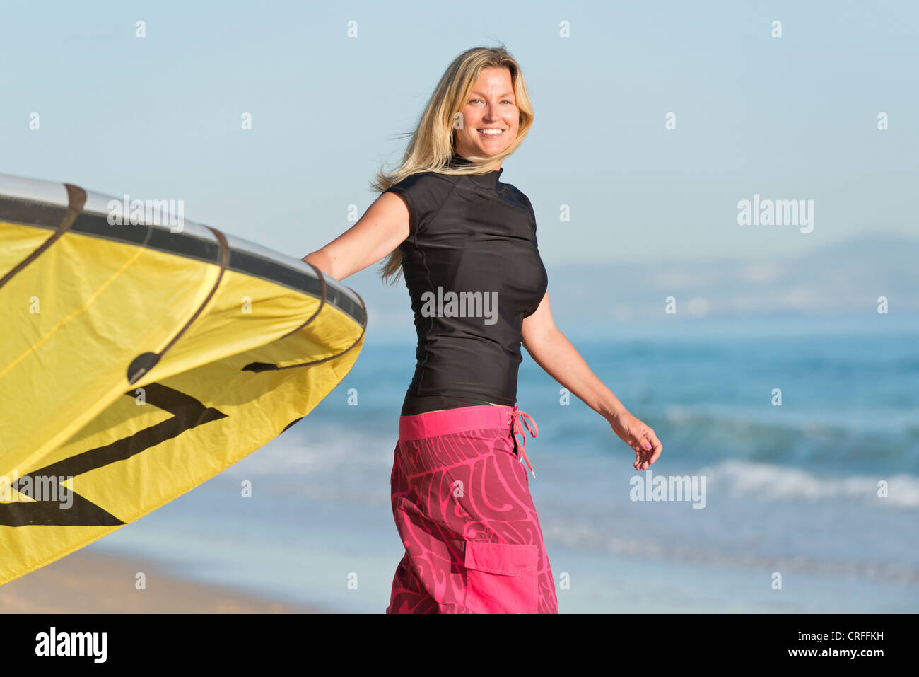 Femme blonde avec un cerf-volant sur la plage. Banque D'Images