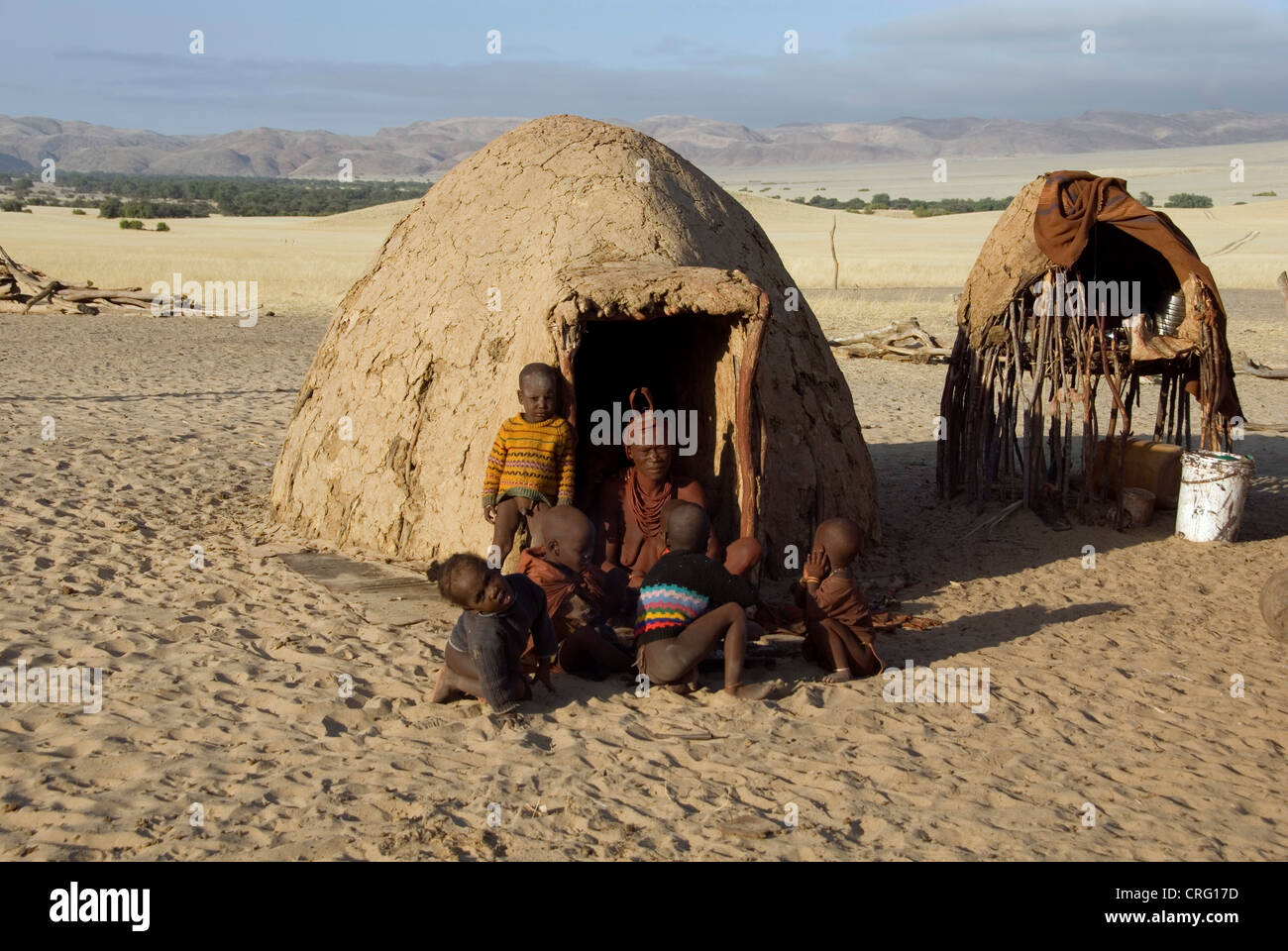 Village traditionnel de Purros, femme Himba avec enfants en face d'une hutte, Namibie, Purros Banque D'Images