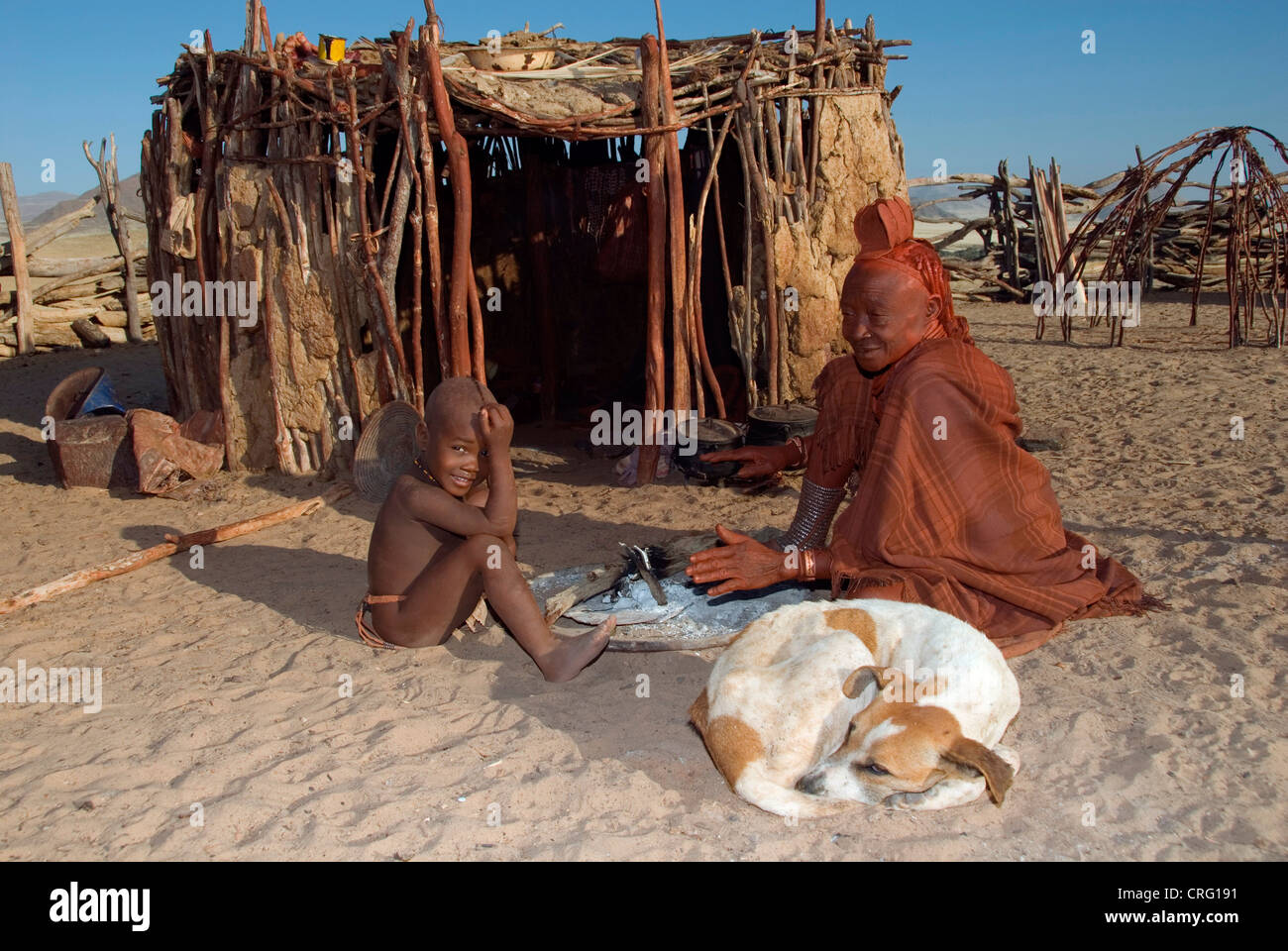 Village traditionnel de Purros, Himba femme avec enfant et chien devant d'une hutte, Namibie, Purros Banque D'Images