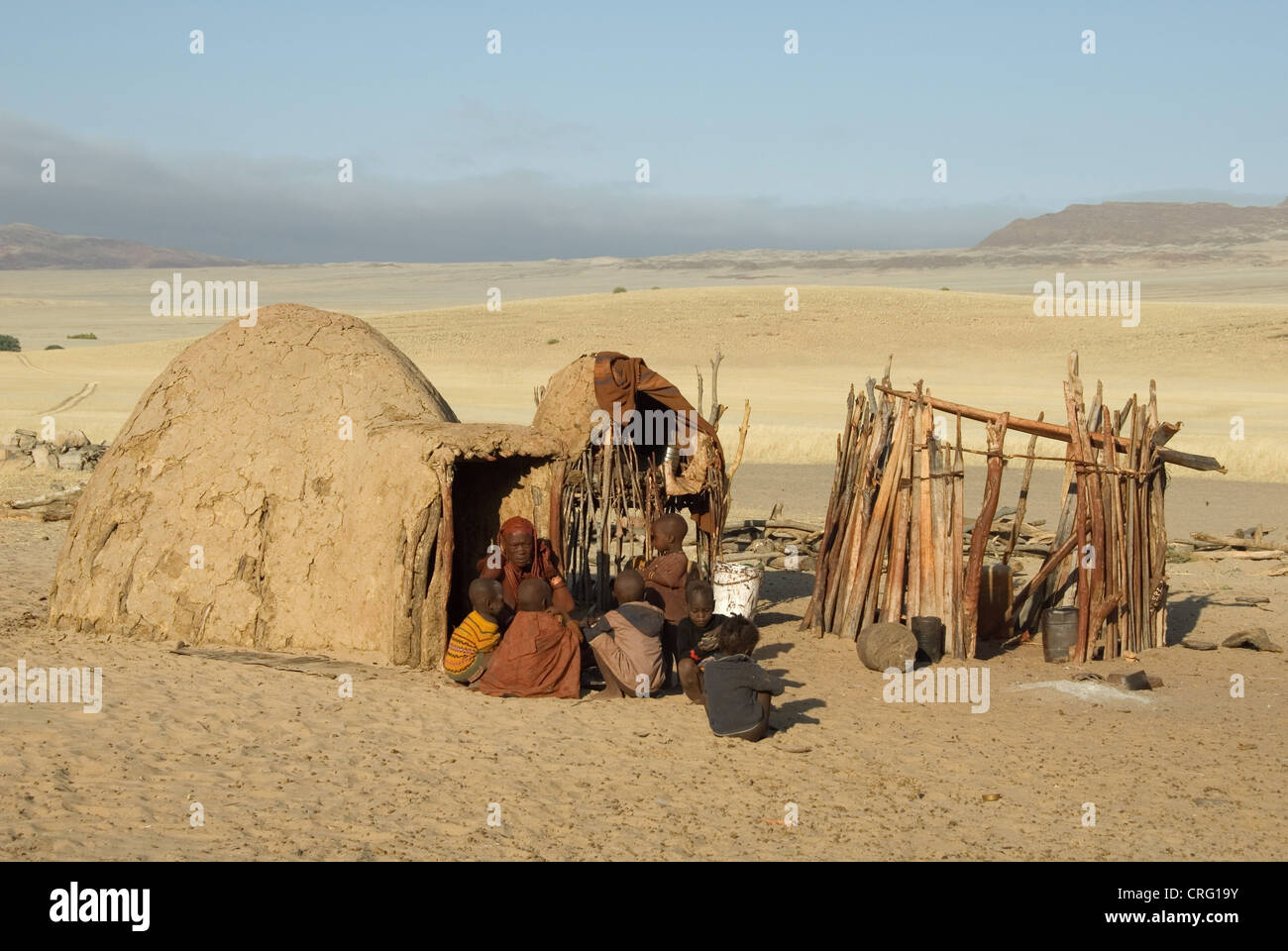 Village traditionnel de Purros, femme Himba avec enfants en face d'une hutte, Namibie, Purros Banque D'Images