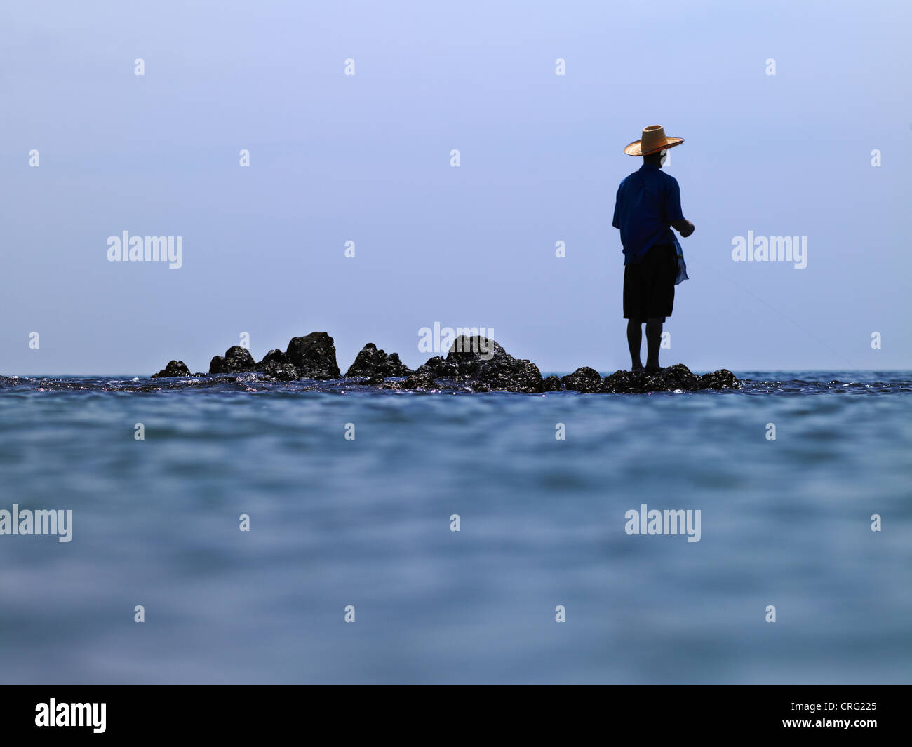 Homme debout sur des rochers dans l'océan Banque D'Images